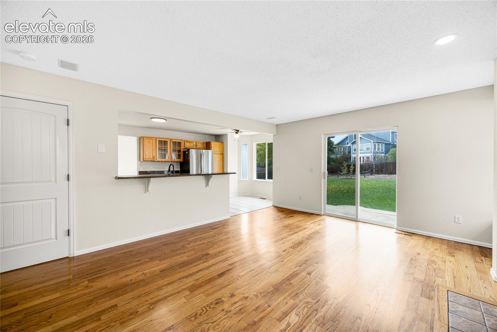 Open-concept living space featuring wood-finish flooring, a breakfast bar, recessed lighting, and sliding glass doors to the exterior