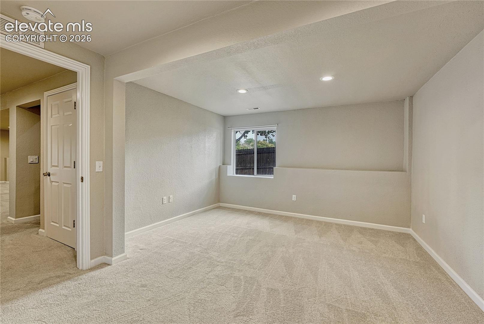 Neutral interior room featuring recessed ceiling lighting, wall-to-wall carpeting, and a single-pane sliding window