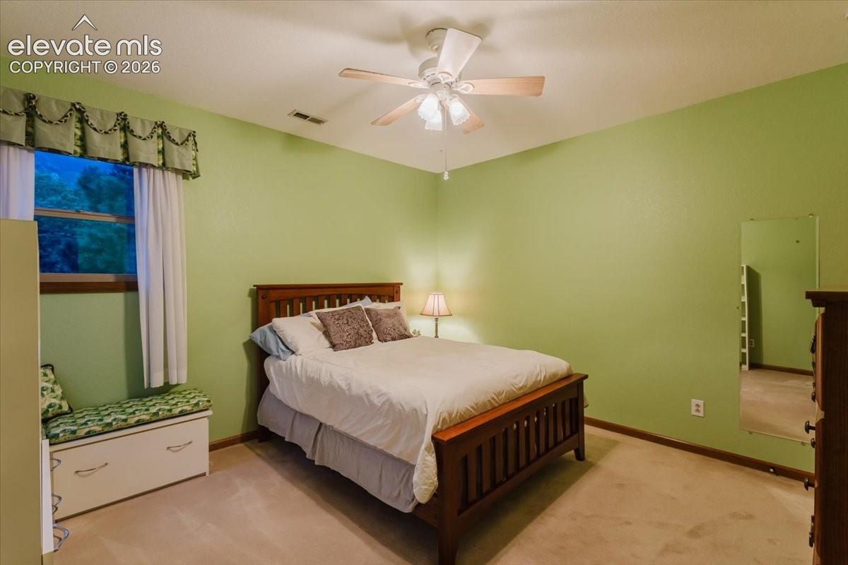 Room featuring a ceiling fan with integrated lighting, a window with a valance and white curtains, and wall-to-wall carpeting