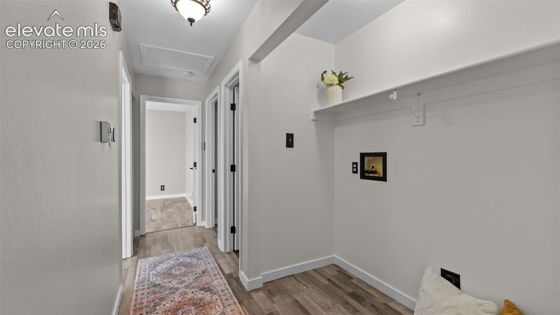 Interior hallway featuring wood-finish flooring, a built-in wall shelf, and neutral wall tones