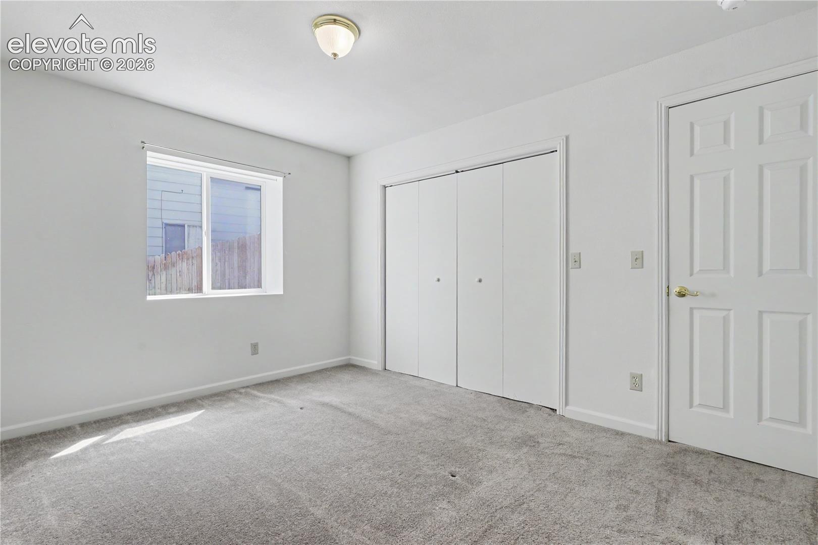 Neutral-toned room featuring a single window, a flush mount ceiling light, and light gray carpet flooring