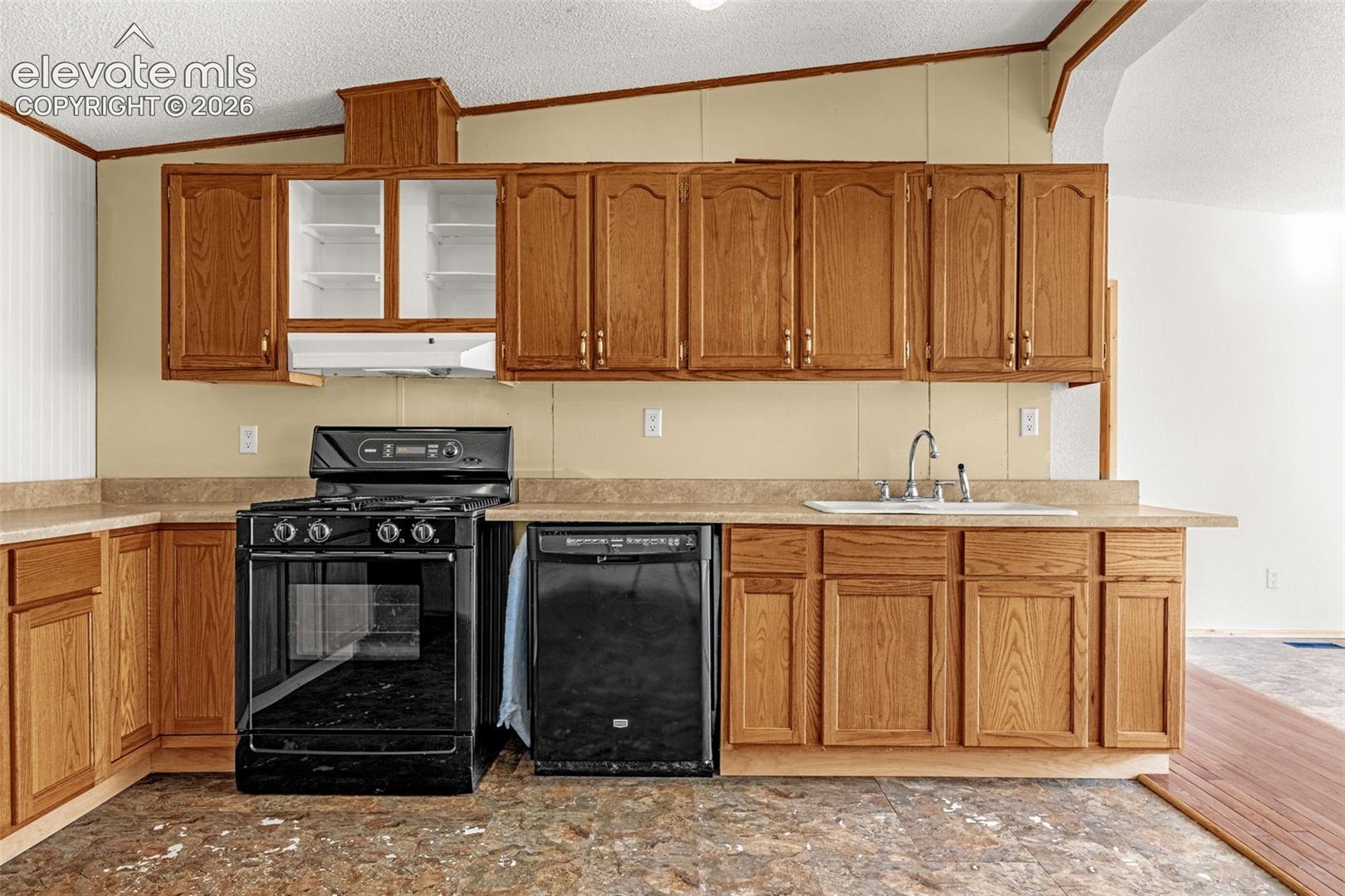 Wood-finish cabinetry with a laminate countertop, a black gas range, and a built-in dishwasher