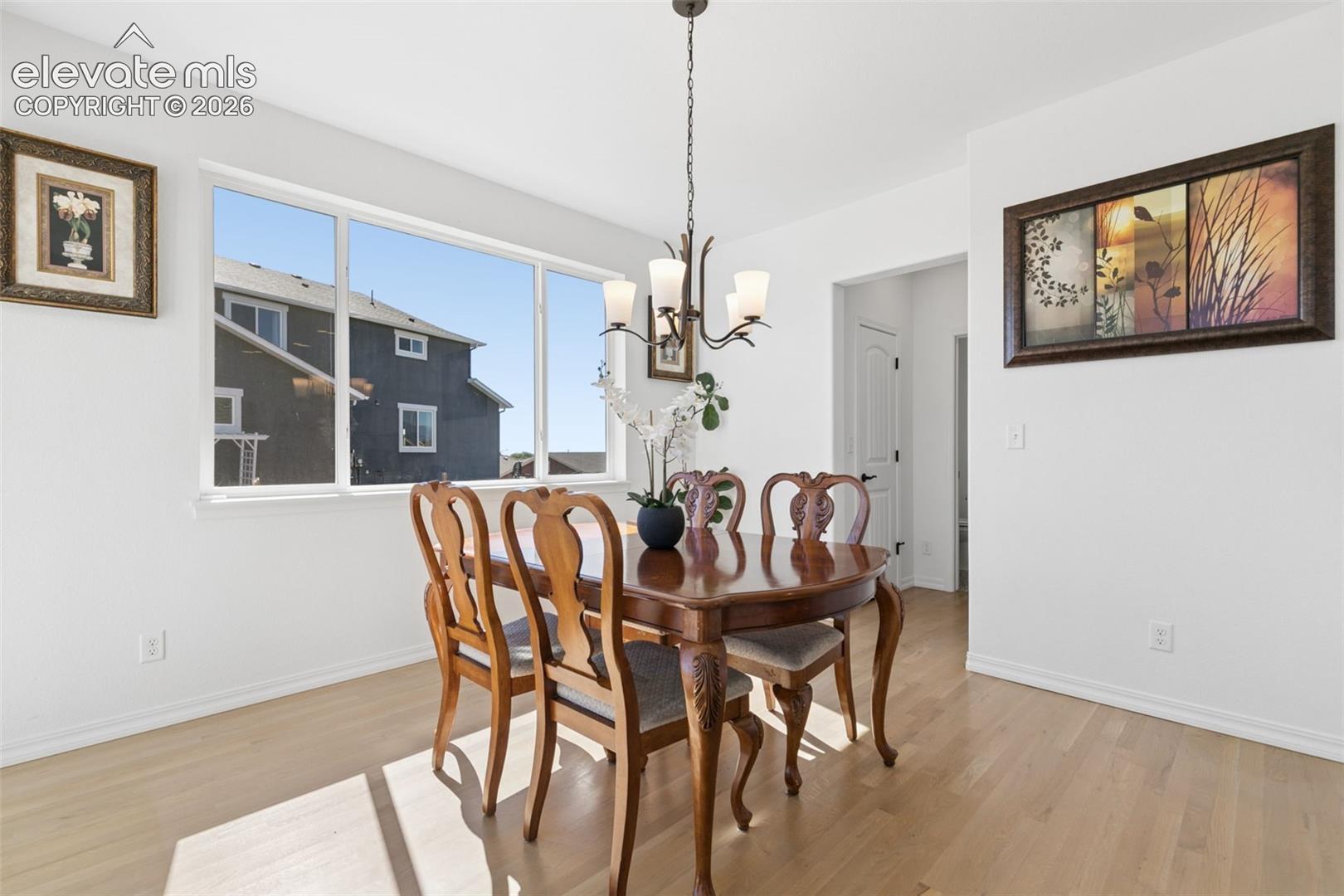  wood-finish flooring, white walls, white trim, and a bronze-finish chandelier