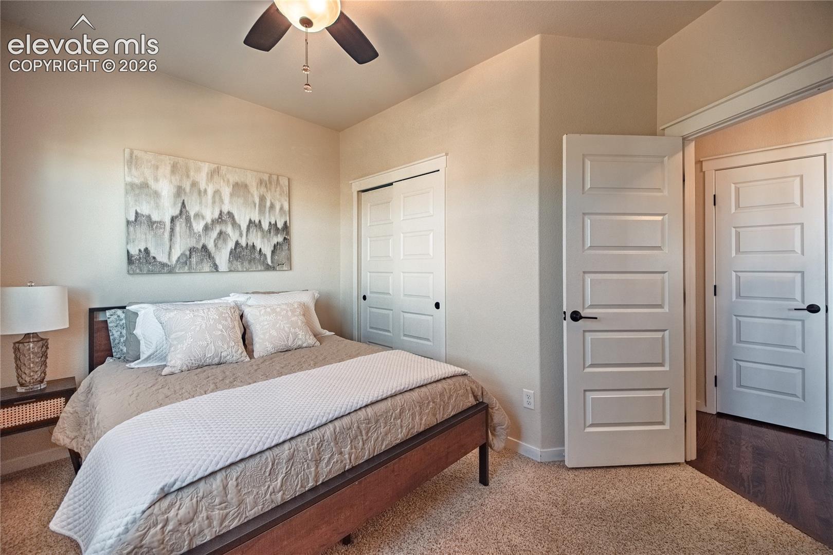 Vaulted ceiling with integrated ceiling fan, five-panel interior doors, and carpeted flooring