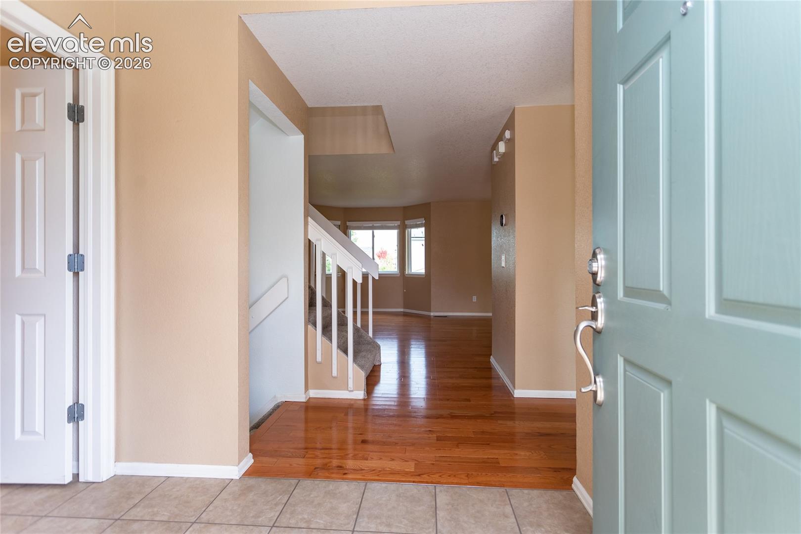 Entryway featuring tile flooring.  1/2 bath to the left, kitchen to the right.