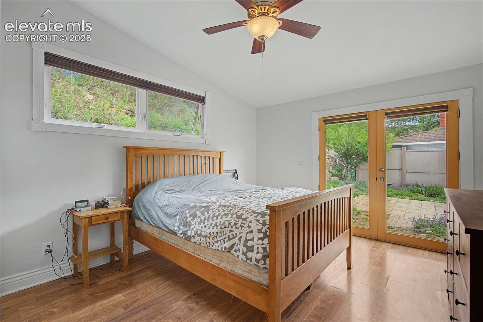 Primary bedroom featuring hardwood flooring and double doors that leads out to the yard.