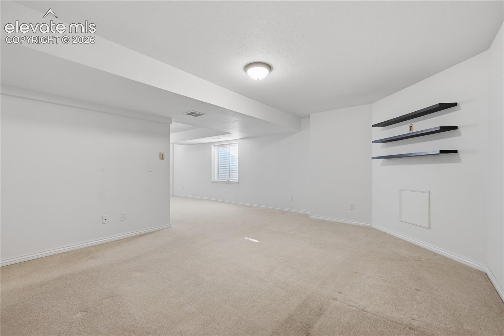 Neutral-toned carpeting, recessed ceiling lighting, and three built-in wall-mounted shelves
