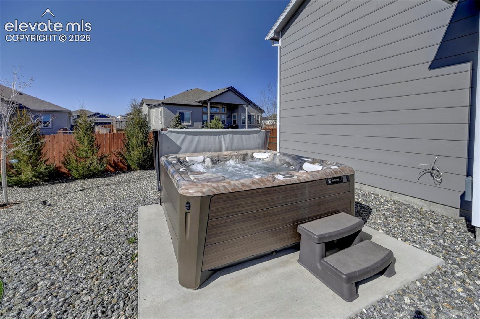 Outdoor spa on a concrete pad, surrounded by grey gravel landscaping