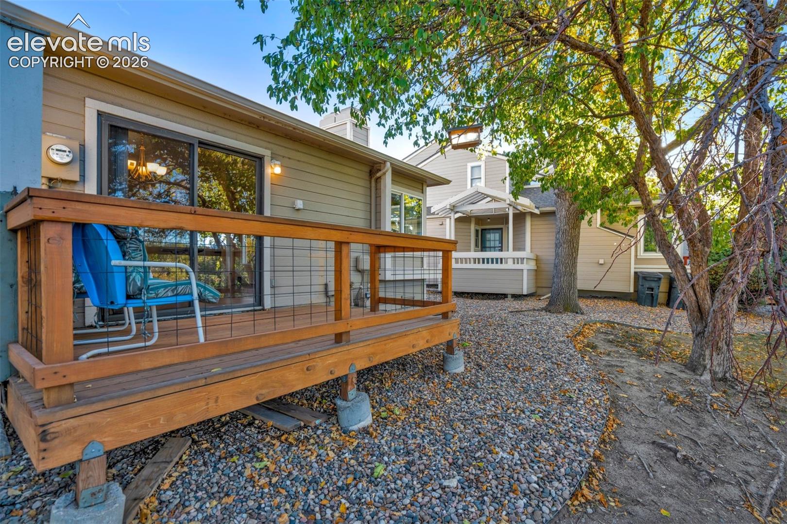 Exterior wood deck featuring wire mesh railing, sliding glass door entry, lap siding, and gravel hardscaping