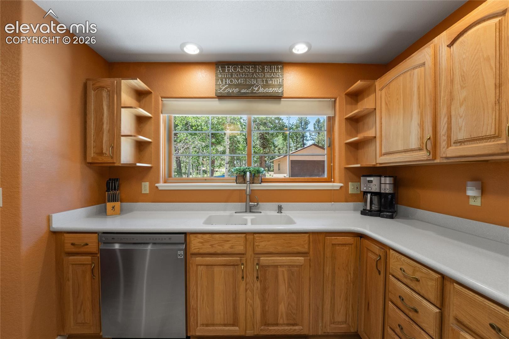 U-shaped kitchen featuring light wood cabinetry, white countertops, and a stainless steel dishwasher