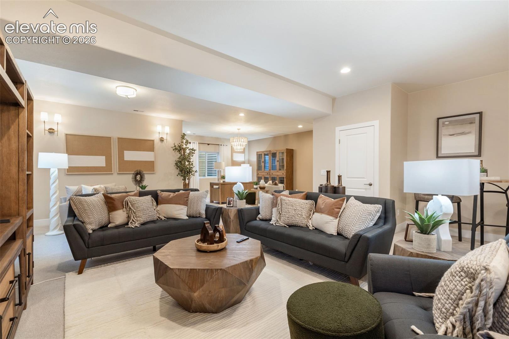 Open-concept room featuring neutral wall color, recessed lighting, wall-mounted light fixtures, wall-to-wall carpeting, and custom built-in wooden shelving