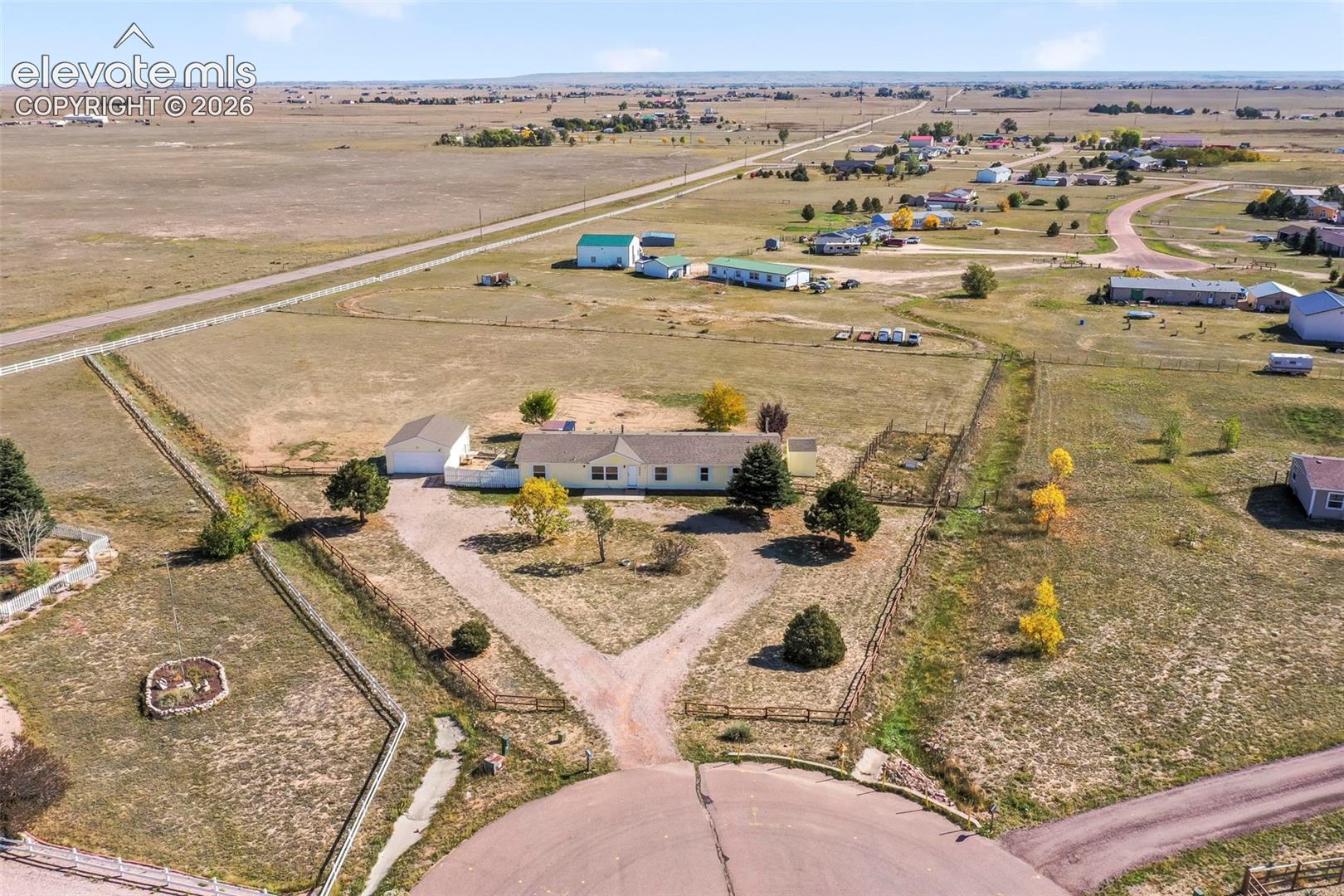 Spacious property featuring a single-story residence, detached garage, and a bifurcated gravel driveway