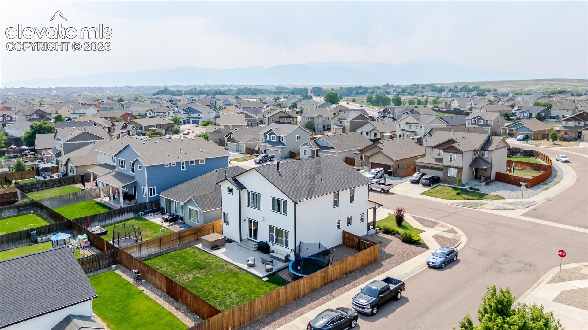 Two-story residence with a light-colored exterior and dark trim, featuring a private fenced backyard with a patio