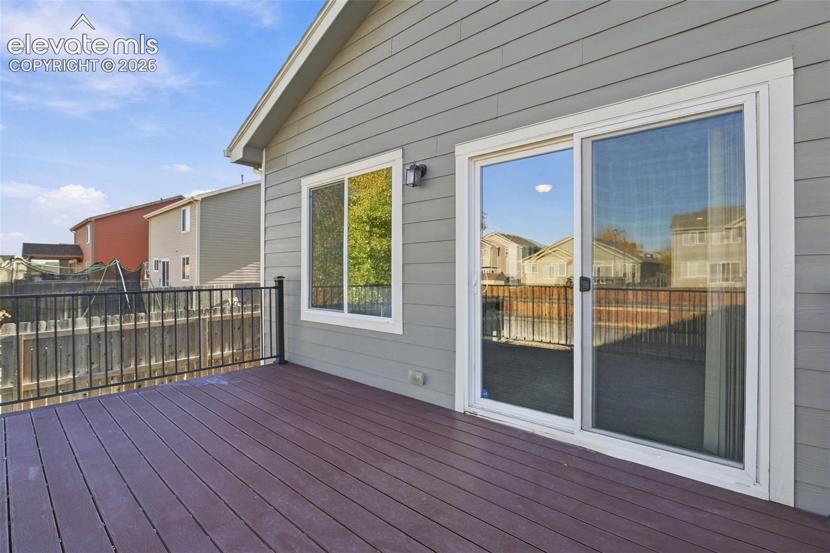 Elevated deck featuring composite planking and a black metal railing, horizontal lap siding, and sliding glass door