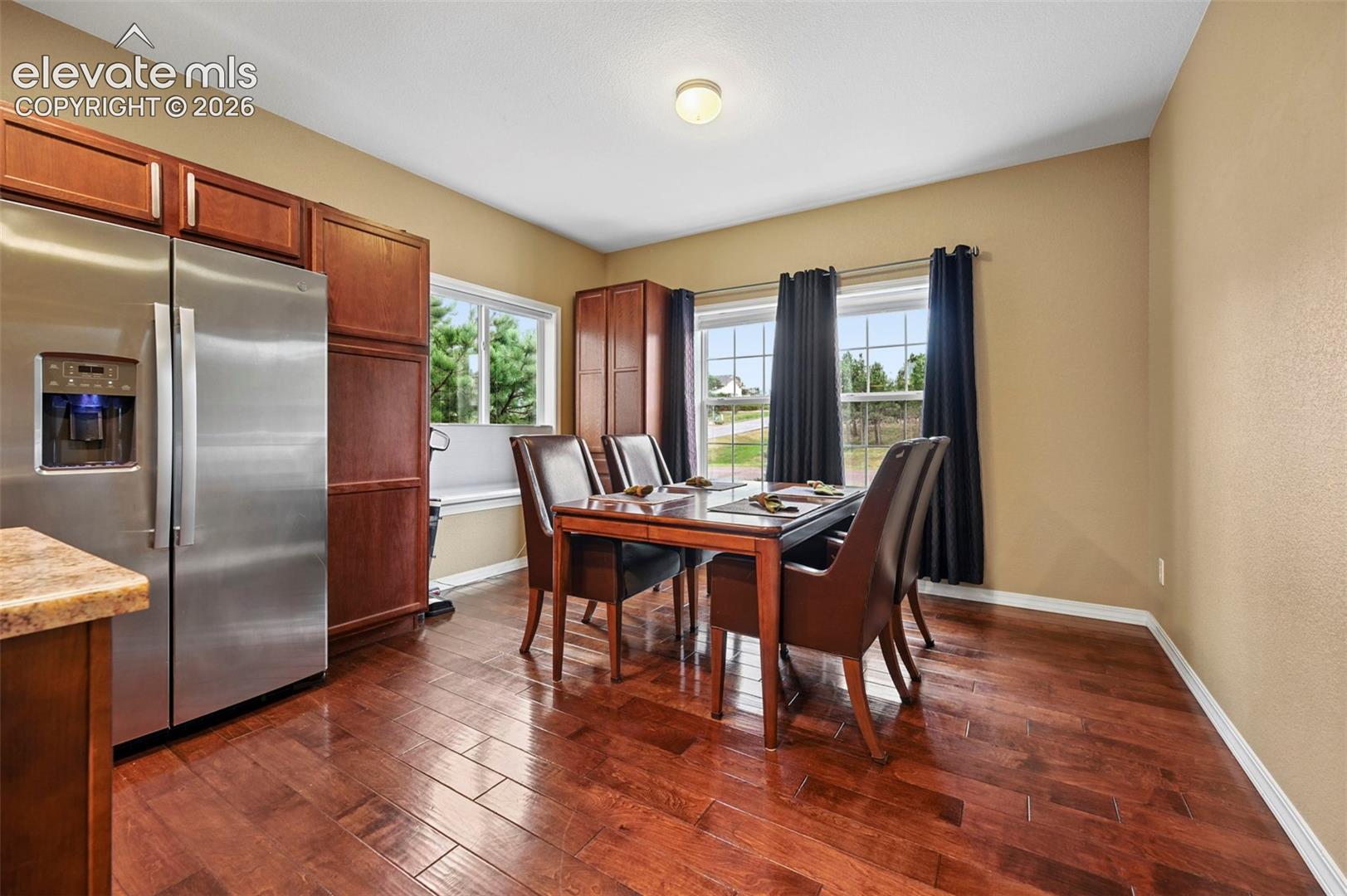 Hardwood-finish flooring, stainless steel refrigerator, abundant cabinetry, and multiple windows