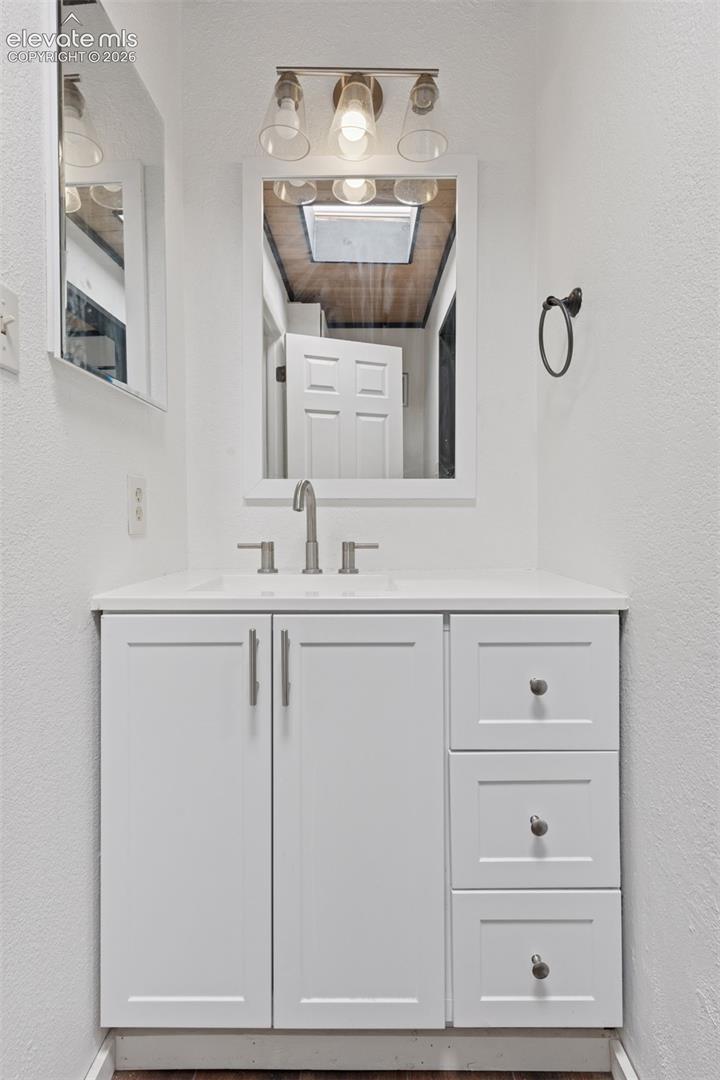 Secondary bathroom with single-sink vanity, mirror, and overhead lighting (similar shower/tub not pictured)