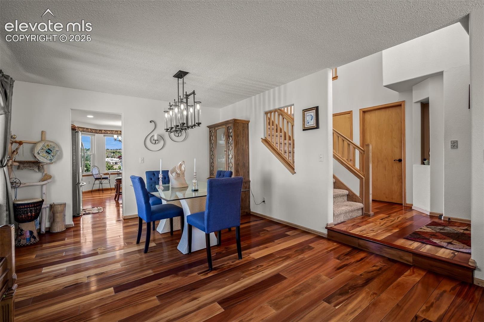 Dining area featuring Brazilian Koa Hardwood flooring, a contemporary chandelier, and the breakfast area windows in the background.