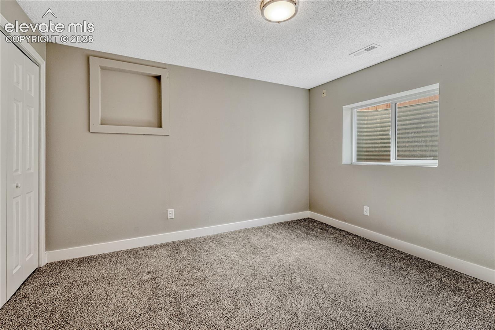 Neutral tone wall paint, textured ceiling, flush mount ceiling light, privacy window, and bi-fold closet doors