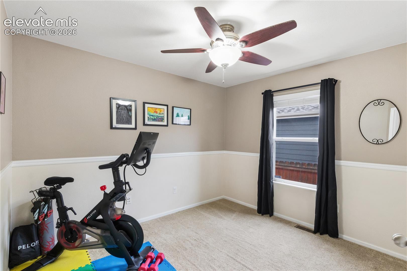 Interior space featuring neutral wall tones, decorative chair rail molding, carpeted flooring, and a ceiling fan with integrated lighting