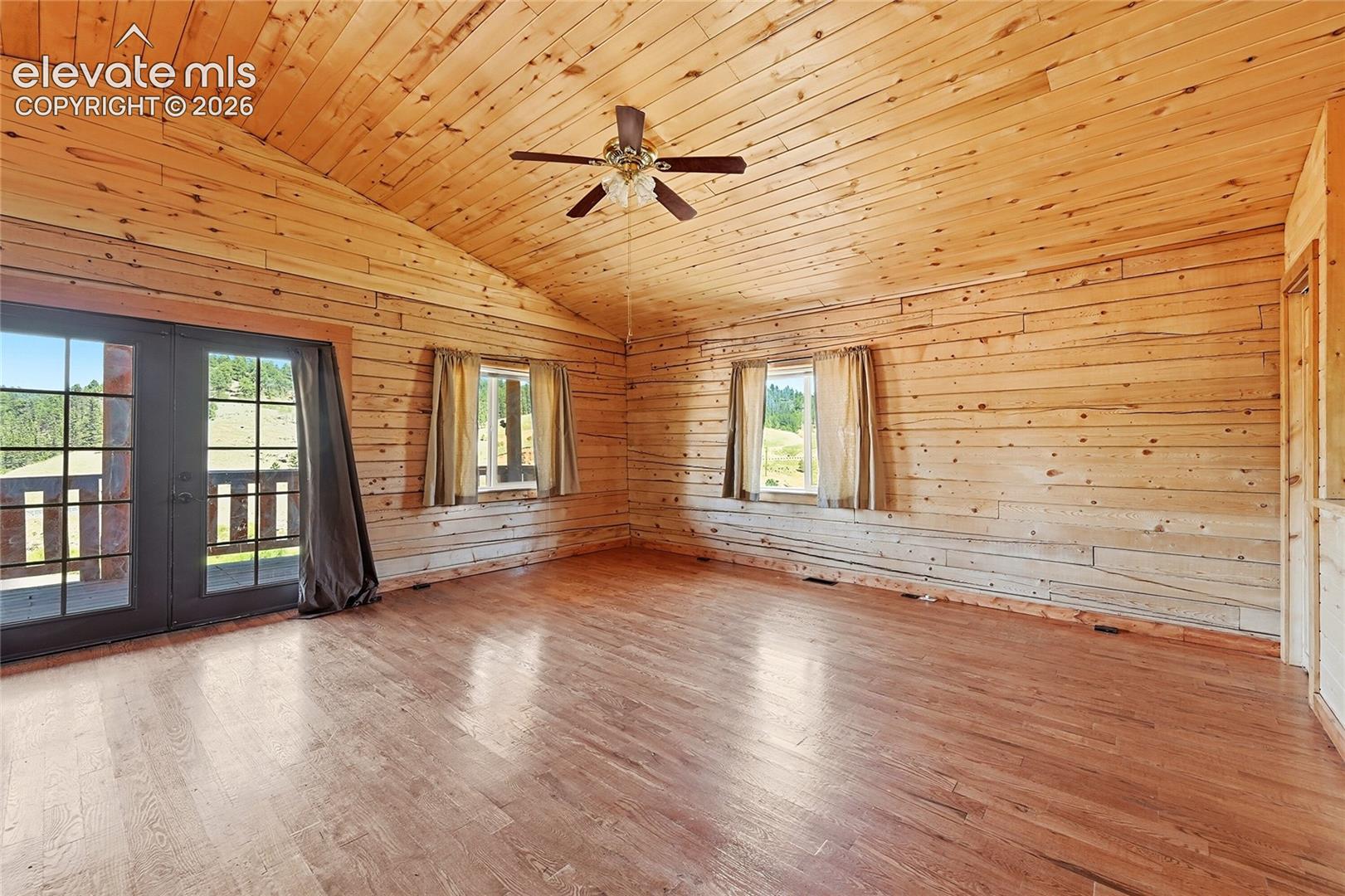 Vaulted wood-paneled ceiling, wood-finish flooring, two windows, and a ceiling fan