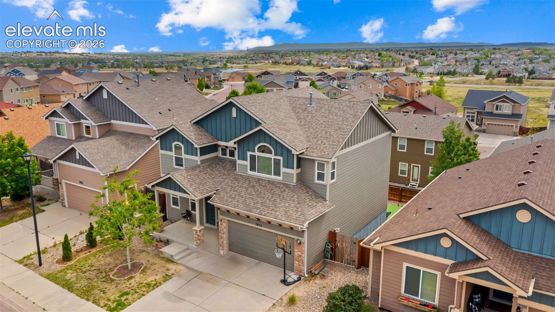Multi-level home featuring a light gray and blue exterior with gabled roofs and a stone facade accent