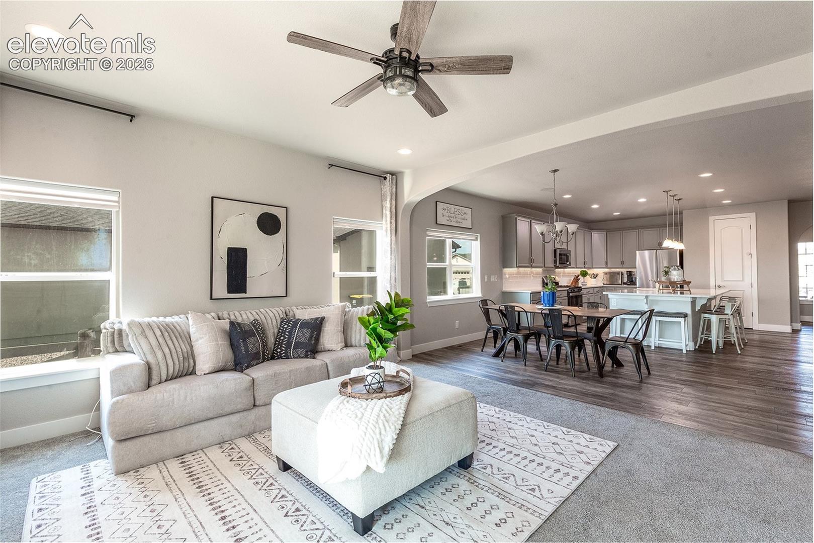 Open-concept living area featuring a ceiling fan, recessed lighting, and large windows