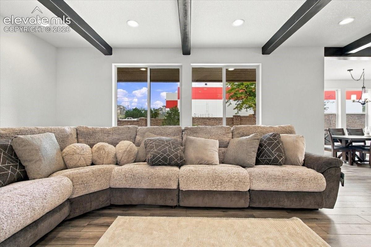 Living area featuring exposed dark-finish ceiling beams, wood-finish flooring, and recessed lighting