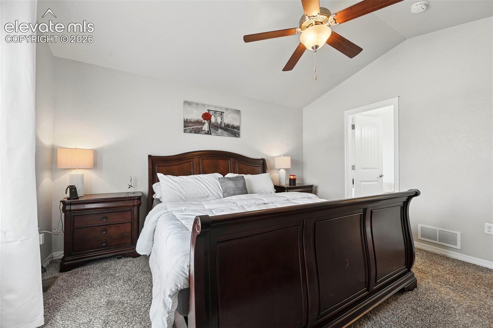 Vaulted ceiling, ceiling fan with integrated lighting, textured carpeting, white painted walls, and white trim