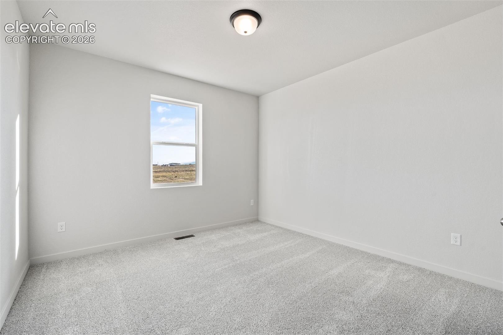 Light gray wall paint, textured carpeting, single window, and flush-mount ceiling light