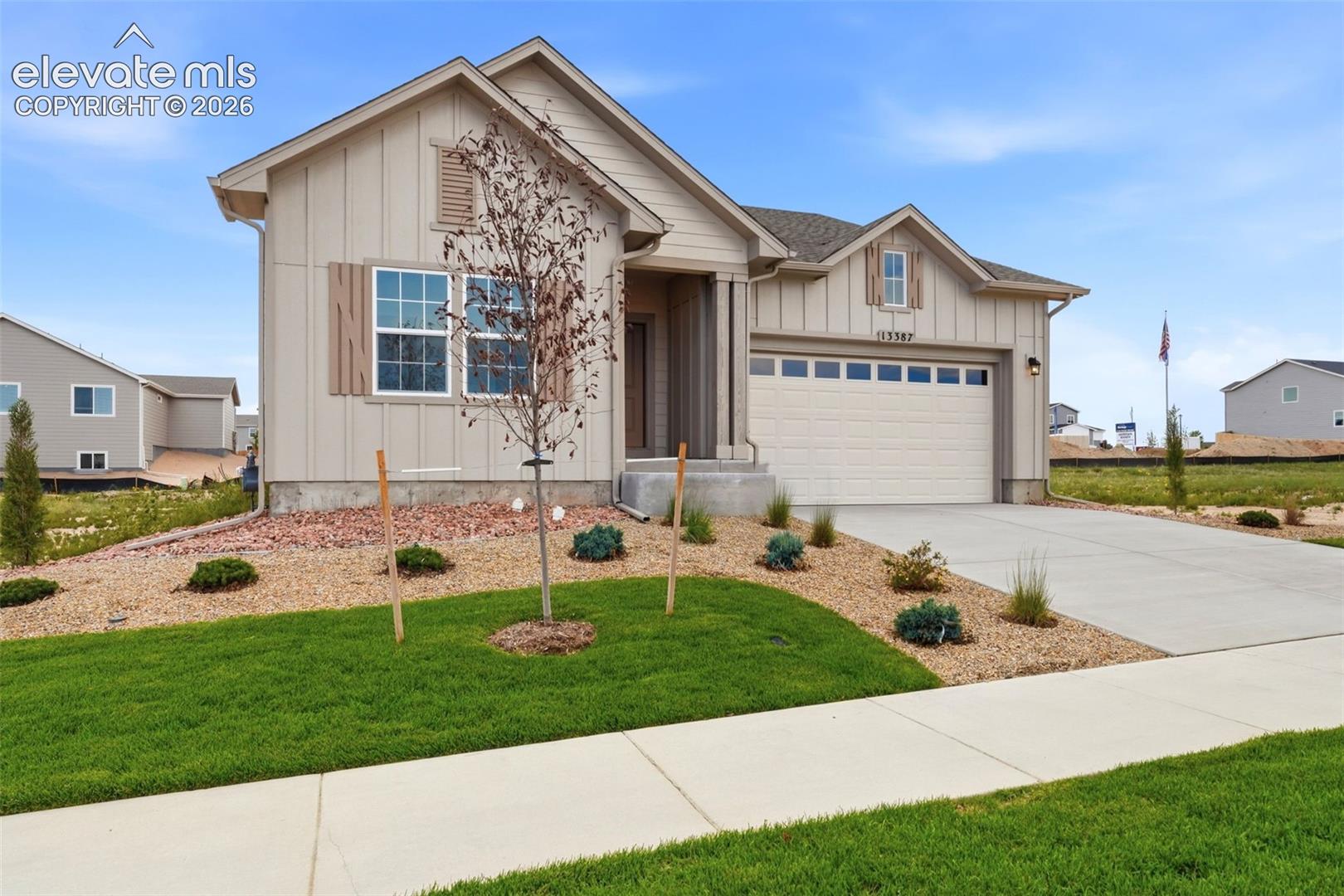 Board and batten siding exterior featuring an attached two-car garage, concrete driveway, and gabled rooflines with decorative shutters