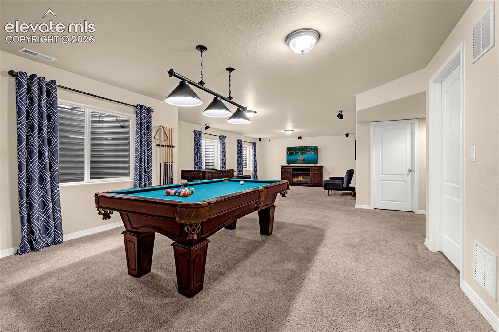 Spacious interior room featuring wall-to-wall carpeting, recessed ceiling lighting, three-paneled interior doors, and a multi-light industrial-style pendant fixture