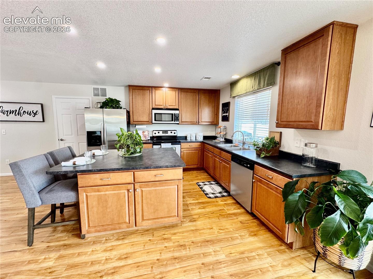 Kitchen featuring wood-finish flooring, a central island with integrated seating, wood cabinetry, and stainless steel appliances