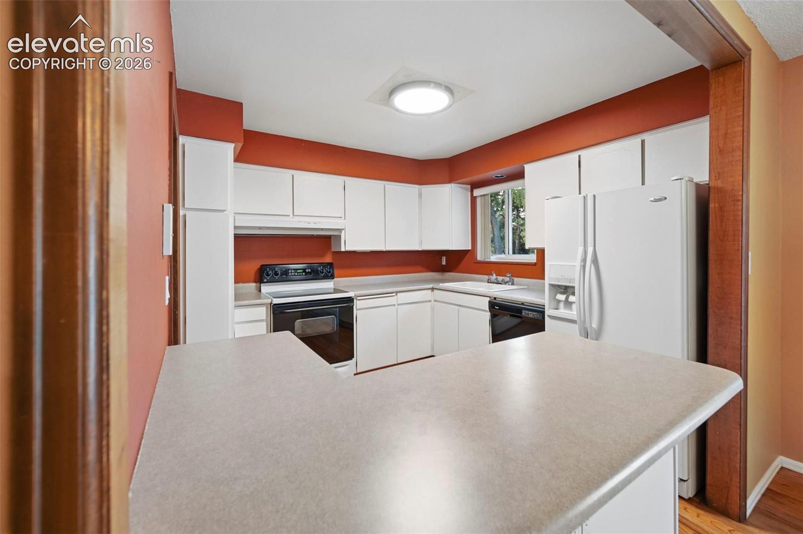 Kitchen with white cabinetry, formica countertops, and all appliances
