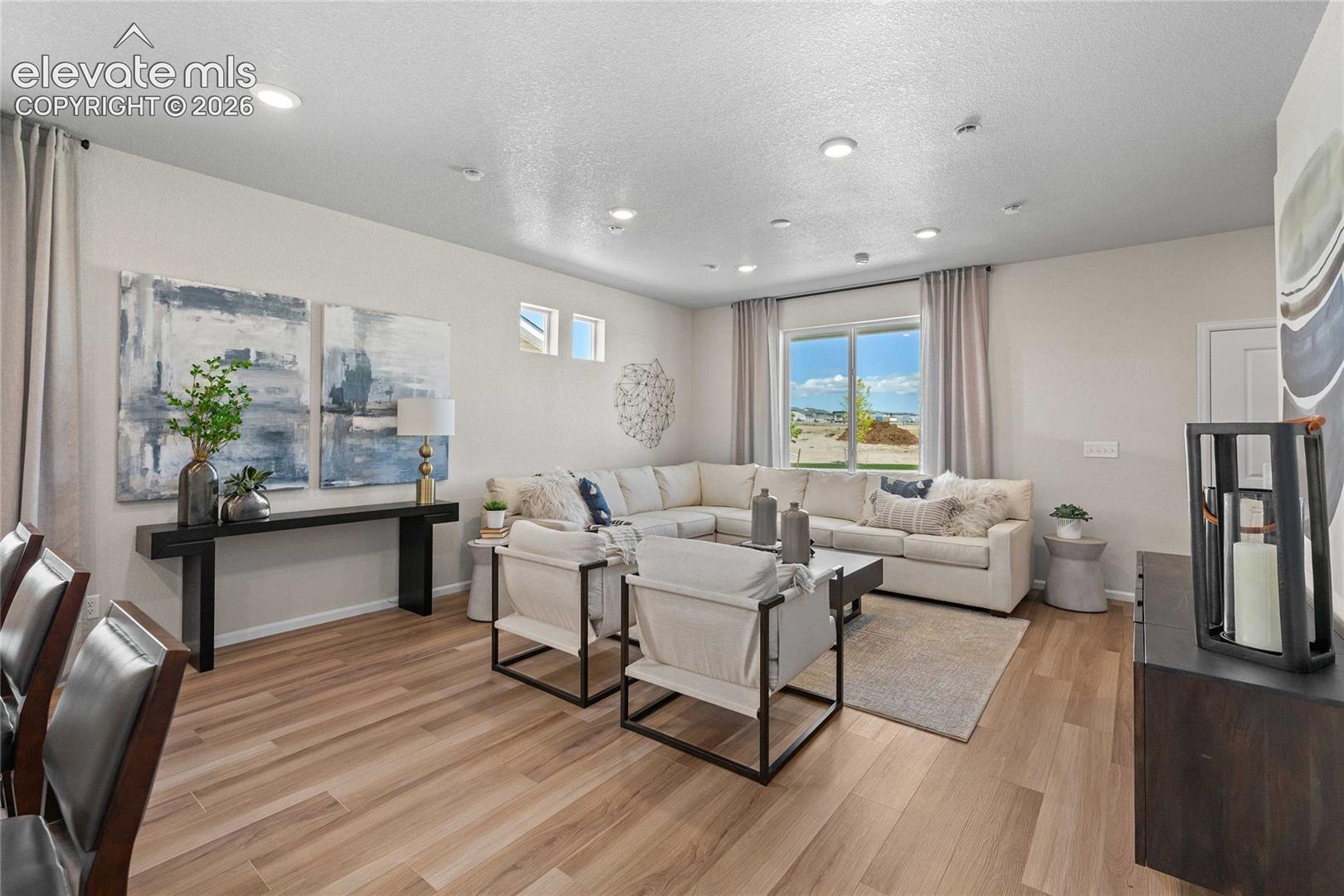 Open-concept interior featuring wood-finish flooring, recessed lighting, and large dual-pane windows
*photos of a model home*