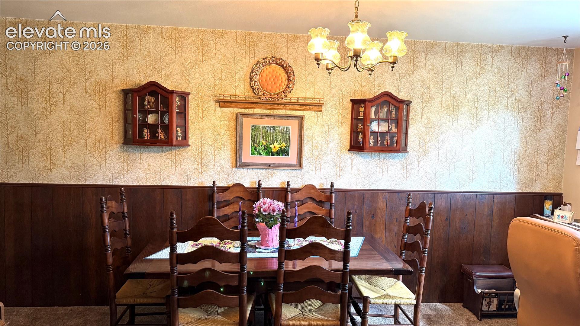 Dining area featuring a wood-panel accent wall and patterned wallpaper