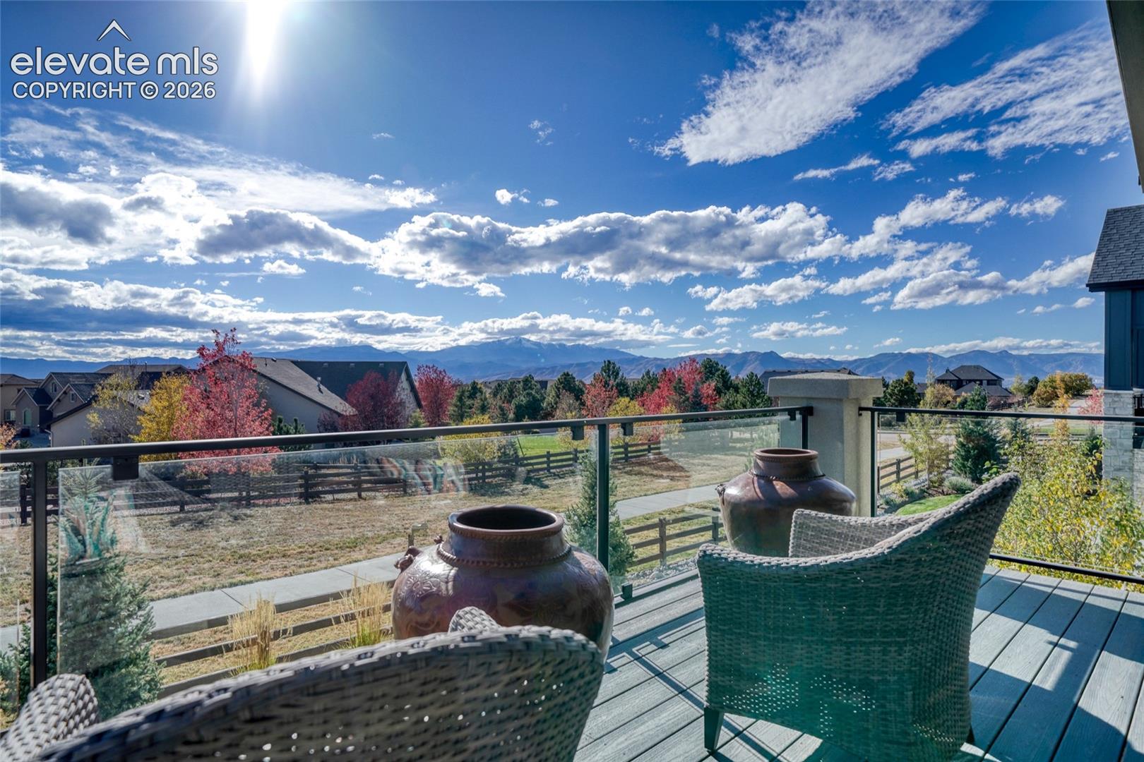 Elevated outdoor deck featuring composite decking, glass panel railing, and mountain backdrop
