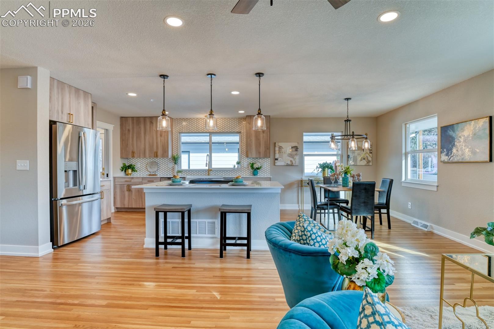 Kitchen featuring pendant lighting, stainless steel refrigerator with ice dispenser, a breakfast bar, and light wood-style flooring