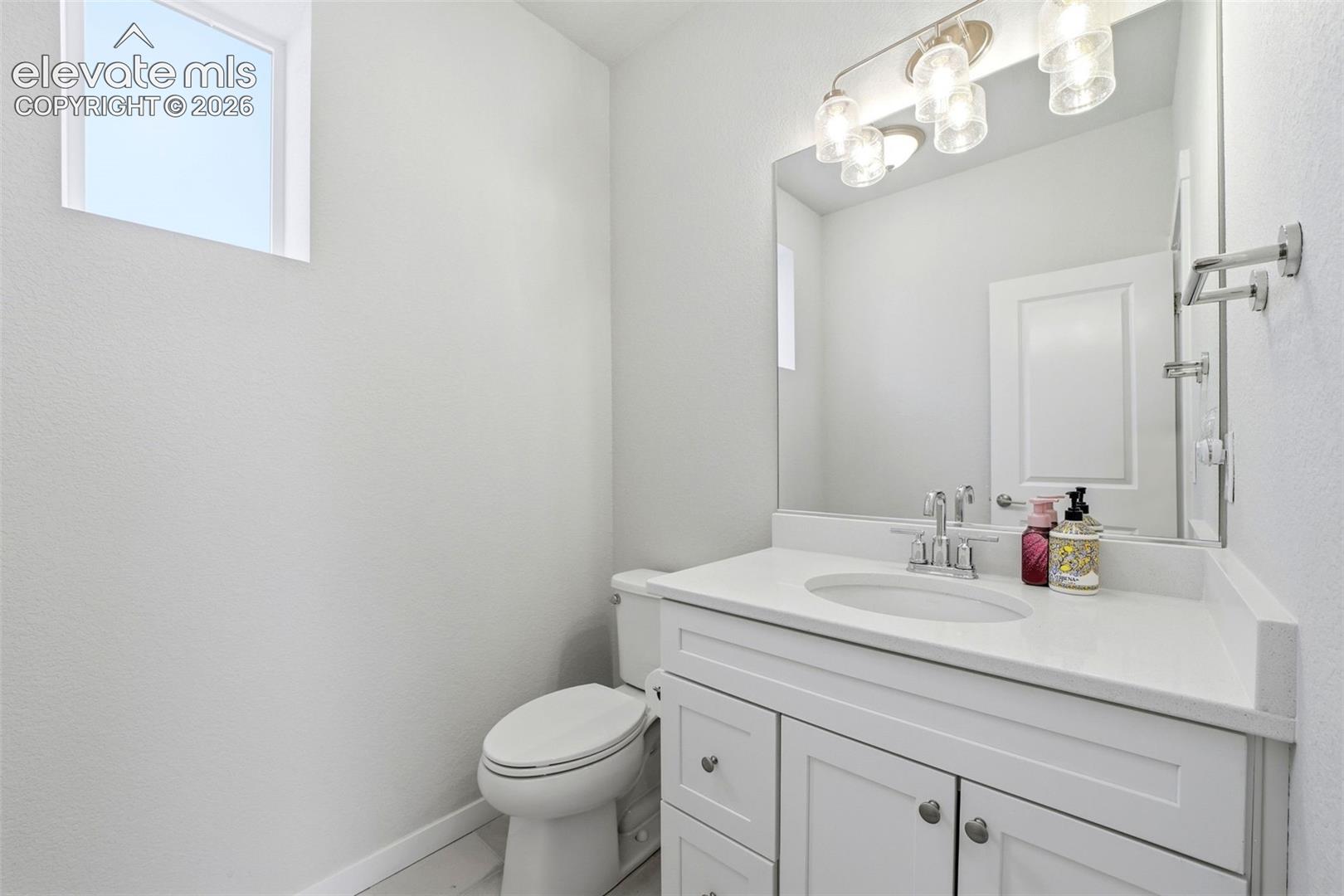 Bathroom Main level 1/2 bath - Vanity with white shaker cabinetry, an integrated sink, and a light-toned countertop