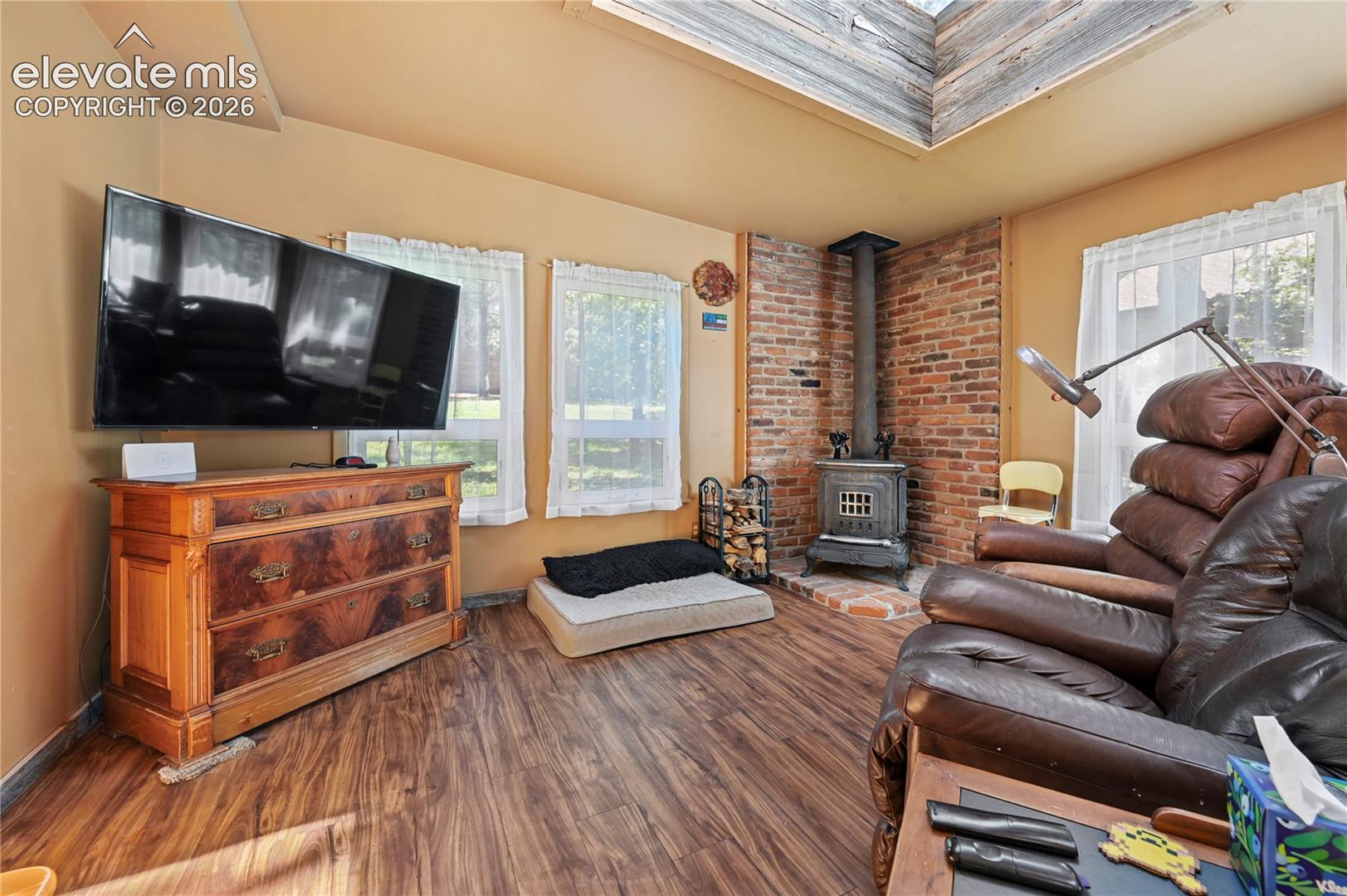 Wood-finish flooring, exposed brick accent wall, and a skylight feature