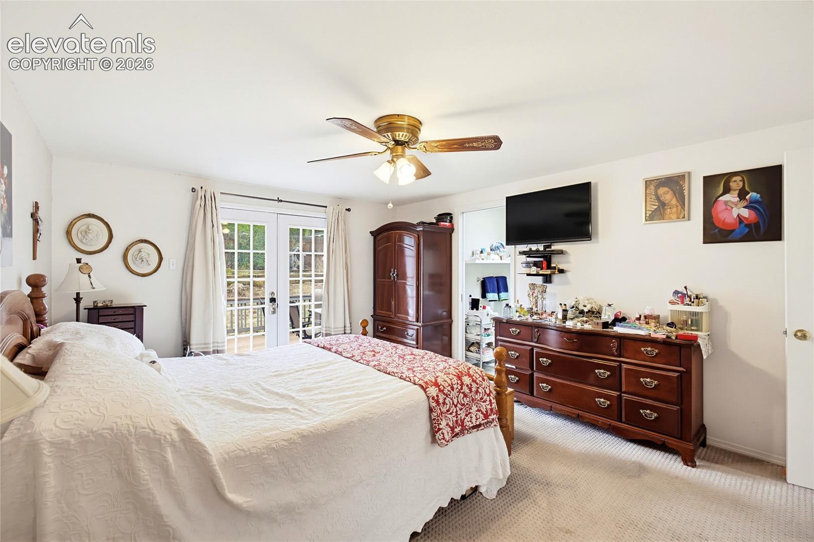 Carpet flooring, ceiling fan with light fixture, and French doors leading to an outdoor area