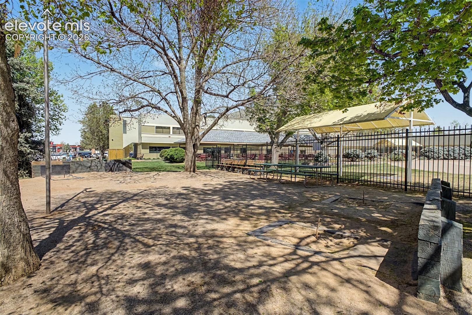 Outdoor area featuring a fenced perimeter, a shade structure, and picnic tables