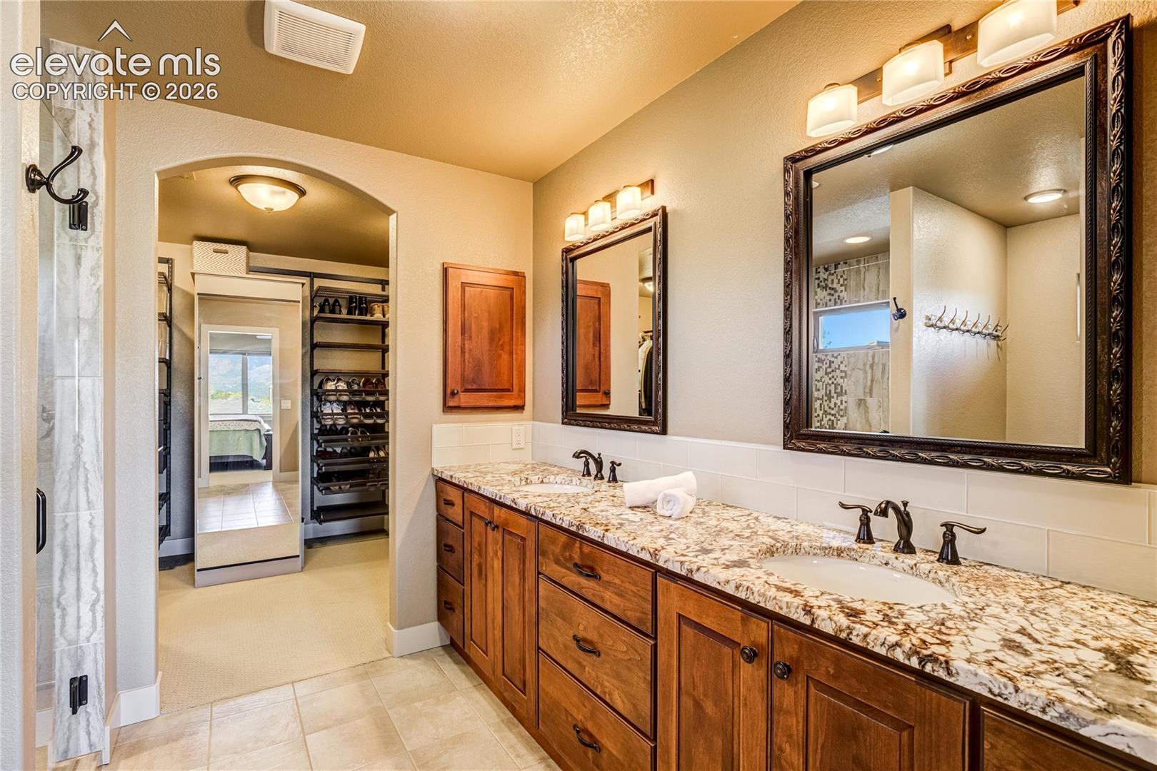 Granite countertops, rich custom cabinetry, decorative mirrors + elegant lighting bring refined finishes and generous storage to the primary bath.