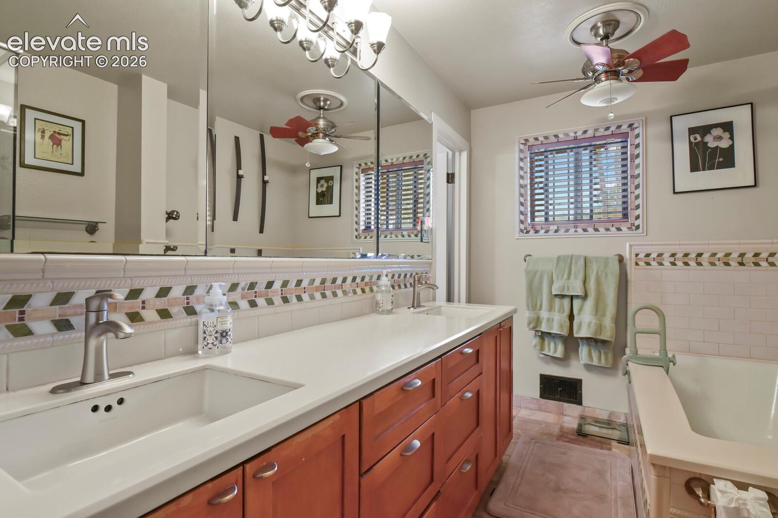 Dual sinks with chrome fixtures, wood-finish cabinetry, and a white countertop