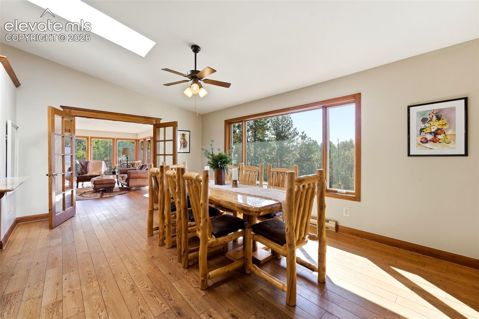 Hardwood flooring, vaulted ceiling, skylight, wood-framed windows, and French doors