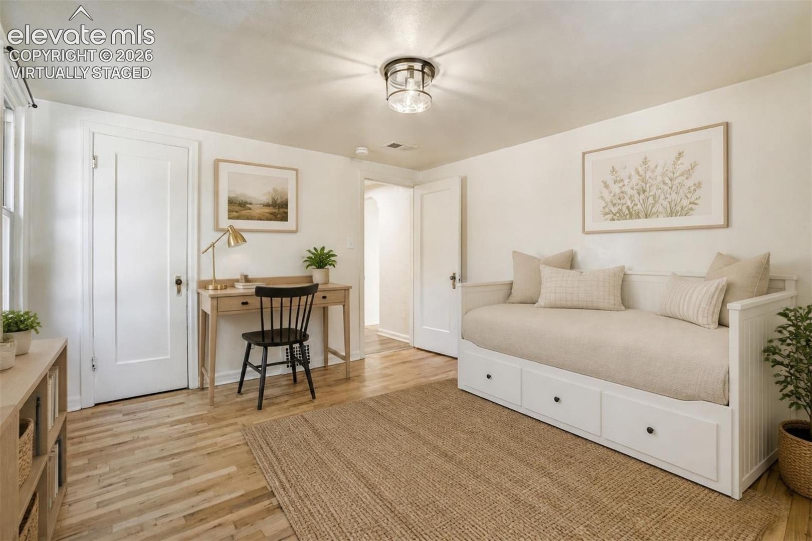 Virtually Staged.  Room featuring wood-finish flooring, white paneled interior doors, and a flush-mount lantern-style light fixture