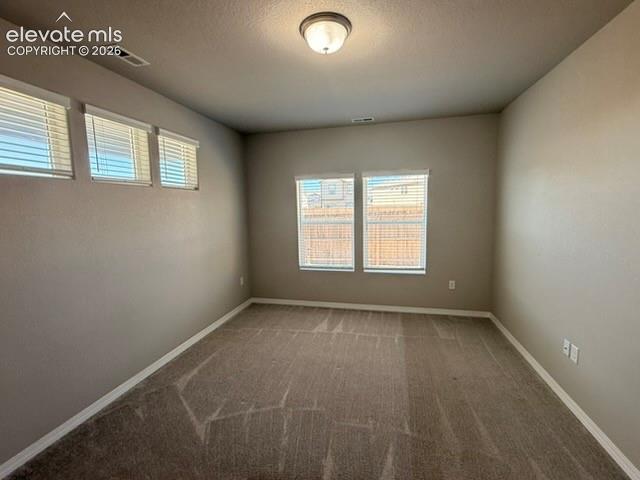 Carpeted interior with neutral wall tones and multiple windows with blinds
