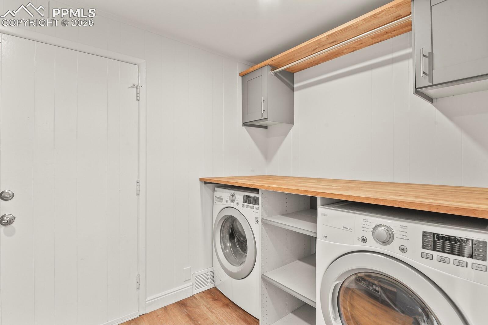 Laundry area featuring a wood counter, cabinets and convenient clothes hanging area