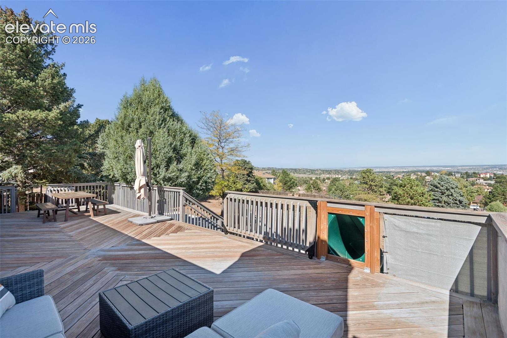 Multi-level wood deck featuring herringbone-patterned decking, perimeter wood railing, and an integrated slide