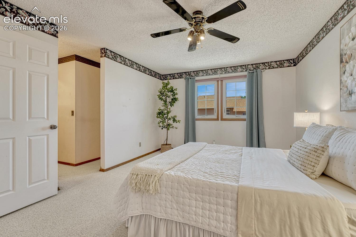 The spacious primary suite features a lighted ceiling fan, walk-in closet, & a private en-suite bathroom 