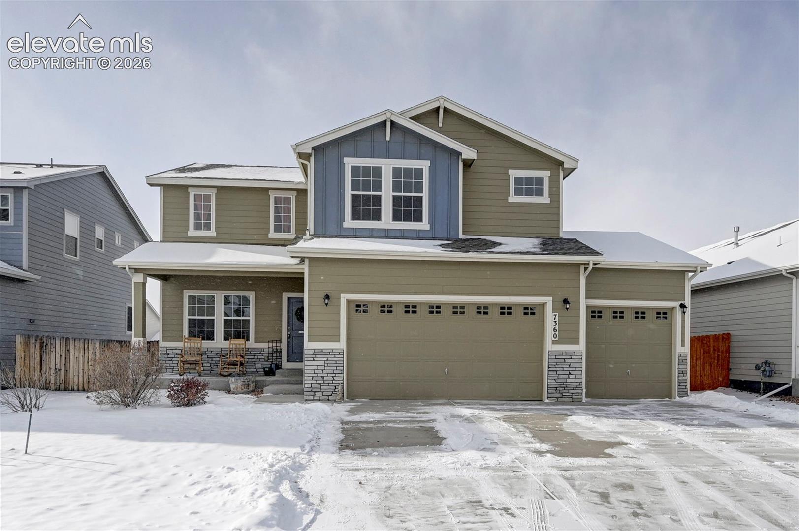 Two-story exterior featuring a mix of horizontal lap siding and vertical board-and-batten accents, stone veneer foundation, multi-gabled roofline, and a three-car attached garage